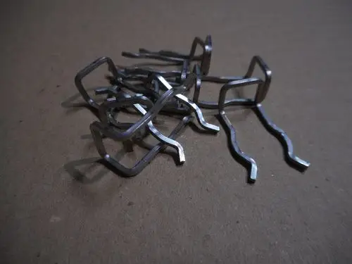 Mehrere metallene Haarnadelfedern liegen auf einer braunen Unterlage. Die Produkte scheinen zur Nutzung in Heizsystemen von Remeha konzipiert zu sein.